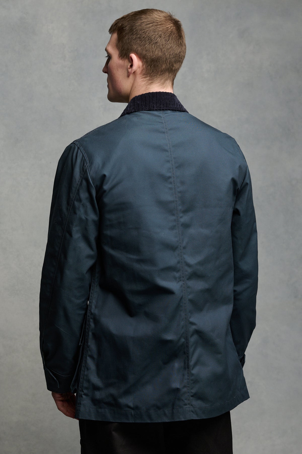 
            Thigh up image of the back of brunet male wearing car coat in navy 