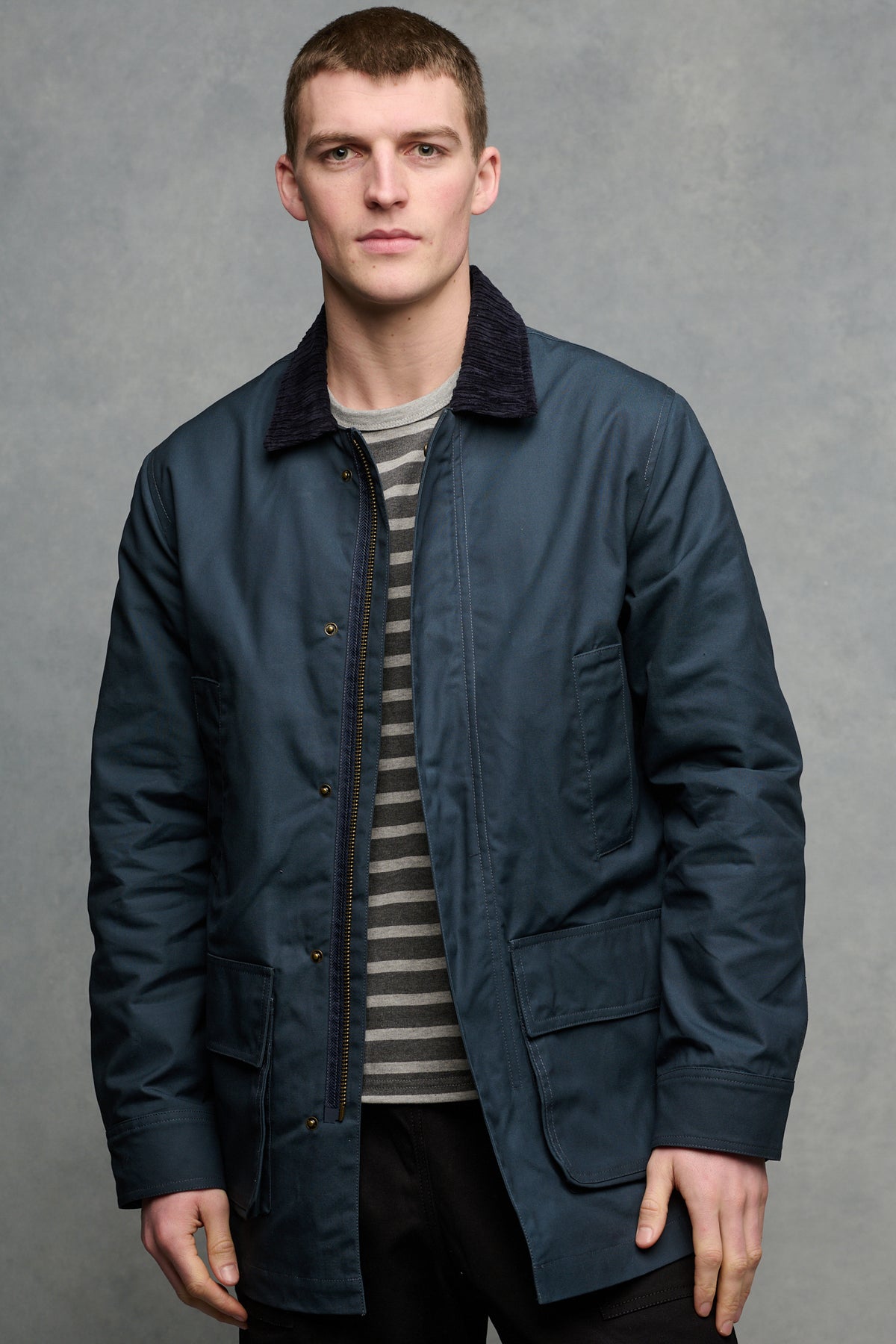 
            Thigh up image of brunet male wearing car coat in navy unzipped open over Breton in charcoal and grey marl