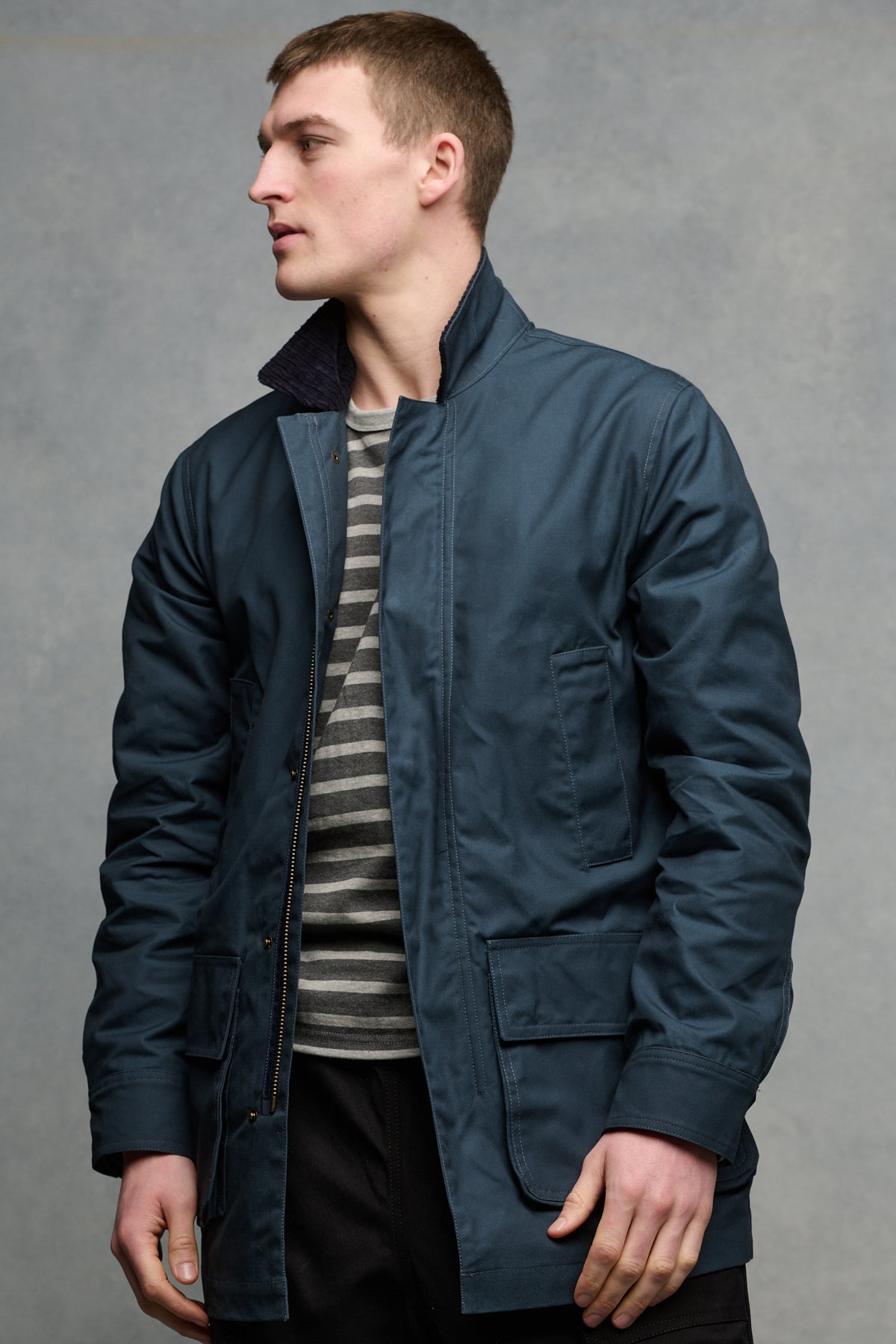 
            Thigh up image of the front of male wearing car coat in navy unzipped over Breton in charcoal and grey