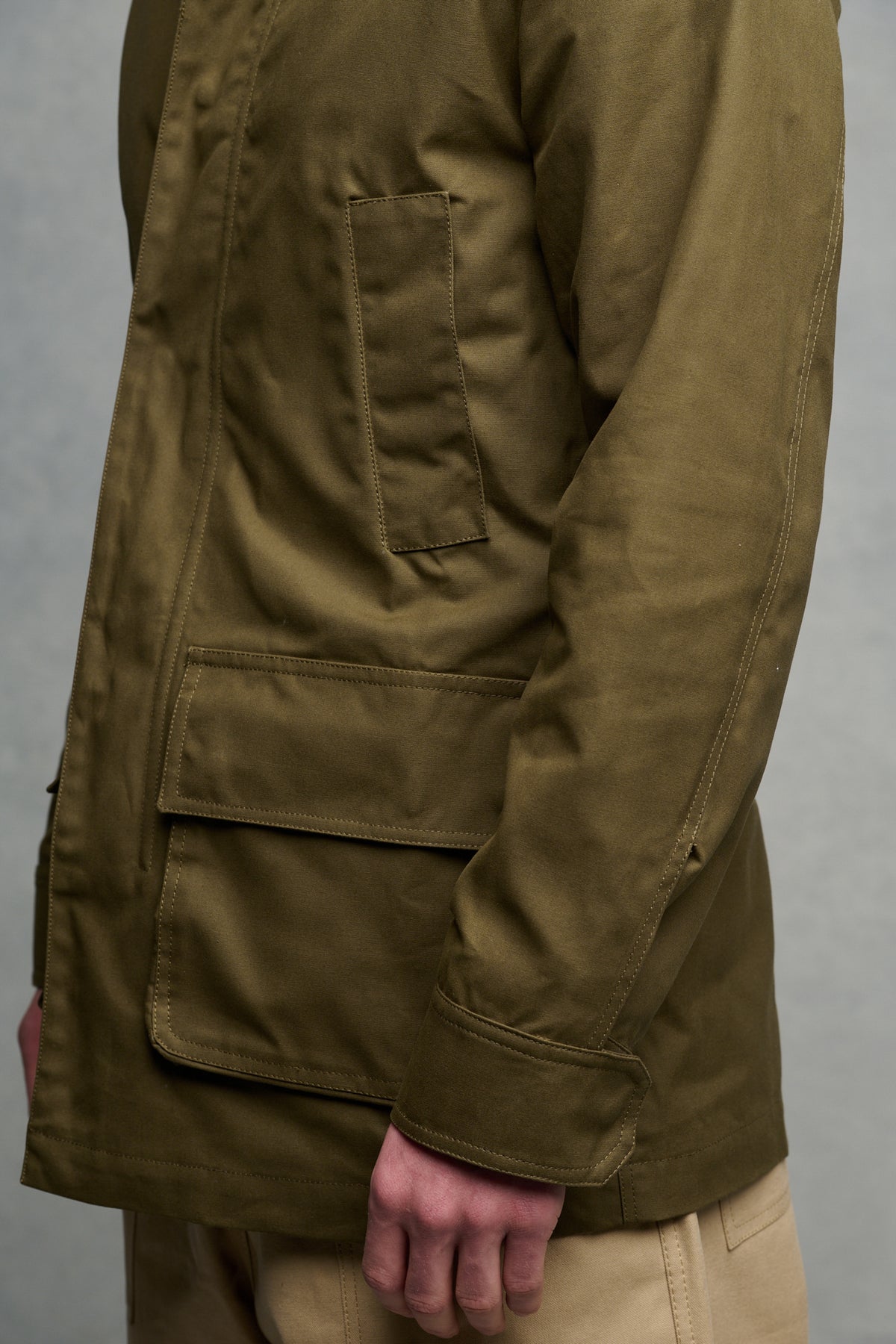Close up of the side of males torso wearing car coat in olive, showing front pockets