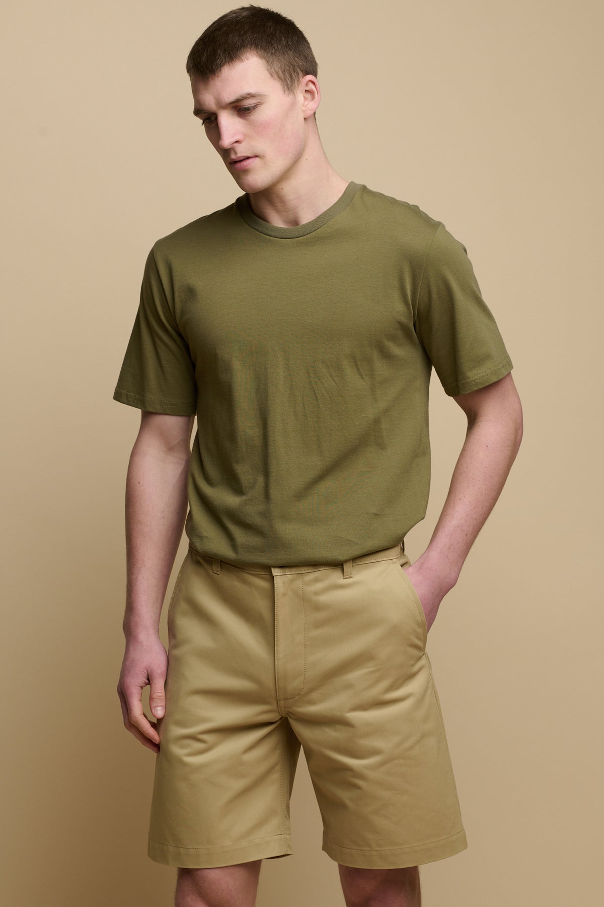 
            Thigh up front facing image of male wearing classic shorts in stone with hand in one of the front pocket and short sleeve t-shirt in olive tucked in