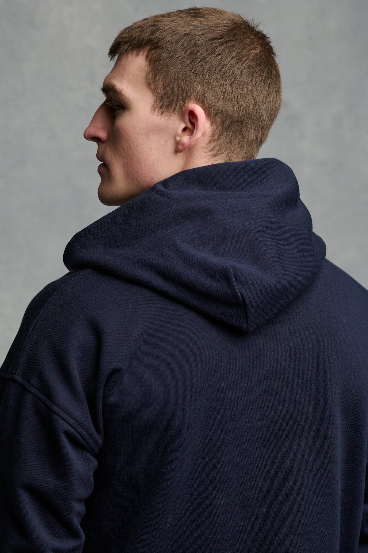 The back of male wearing hooded sweatshirt in navy with hood