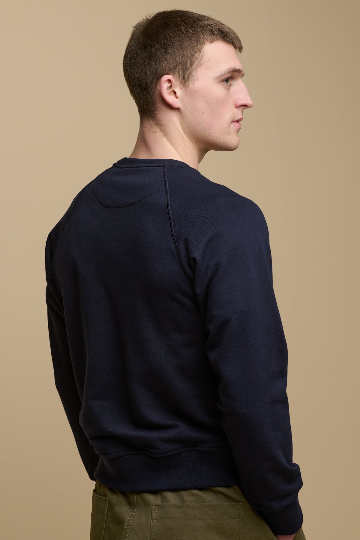 Thigh up of the back of male wearing logo raglan sweatshirt in navy