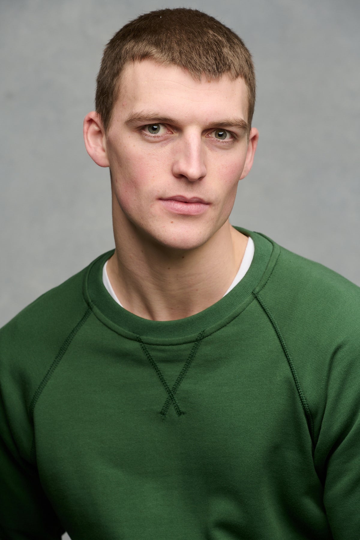 Portrait of male wearing raglan sweatshirt in bottle green worn over crew neck in white