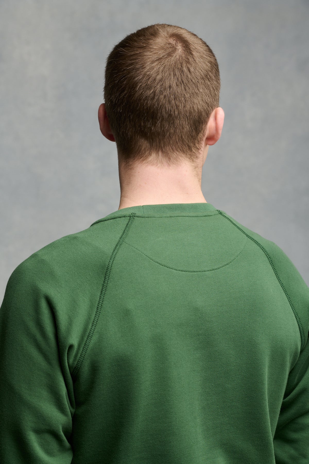 
            The back of male&#39;s shoulders wearing raglan sweatshirt in bottle green