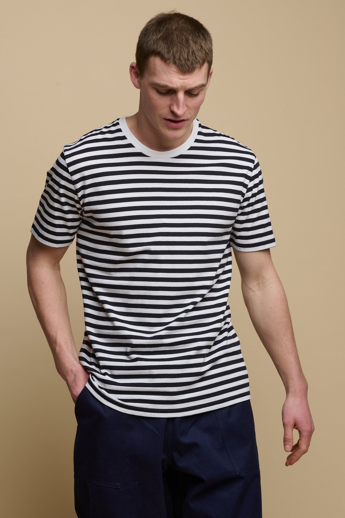 
            Thigh up image of brunet male wearing short sleeve stripe t shirt in navy white