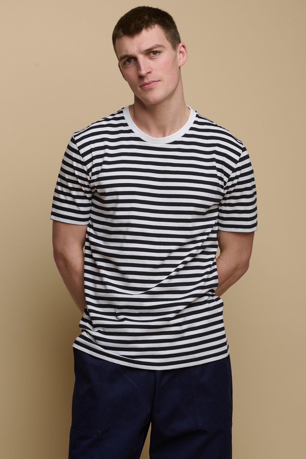 
            Thigh up image of male wearing short sleeve t shirt in navy white stripe paired with cameraman pants in navy