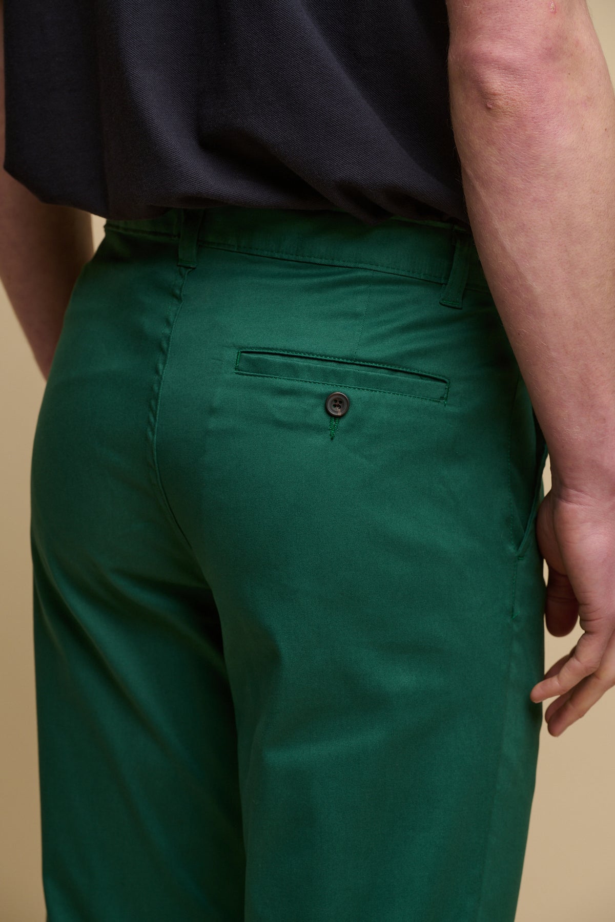 A close up shot of the back of male wearing men's slim stretch chino in bottle green with one back pocket with button fastening on the right