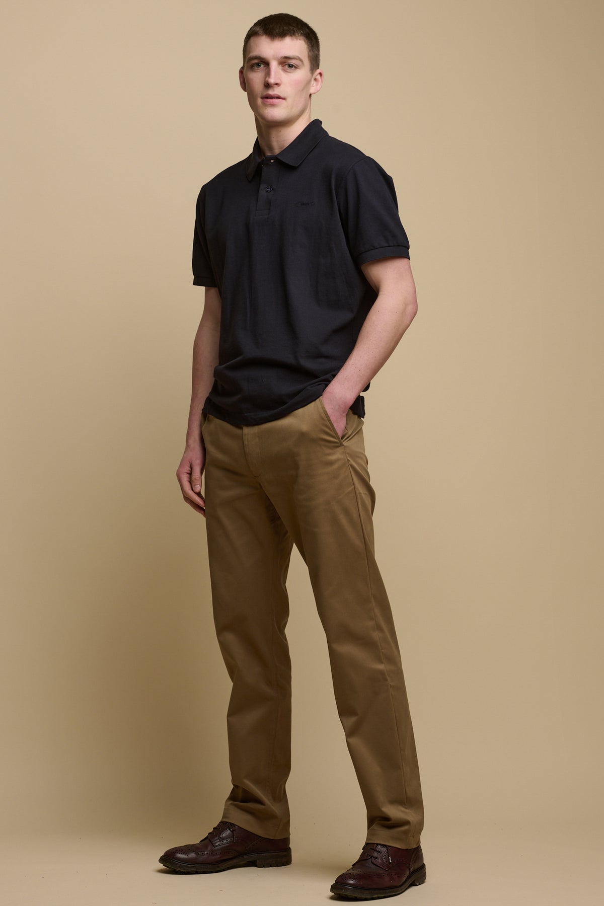 Full body image of male wearing slim stretch chino in khaki worn with short sleeve polo in navy