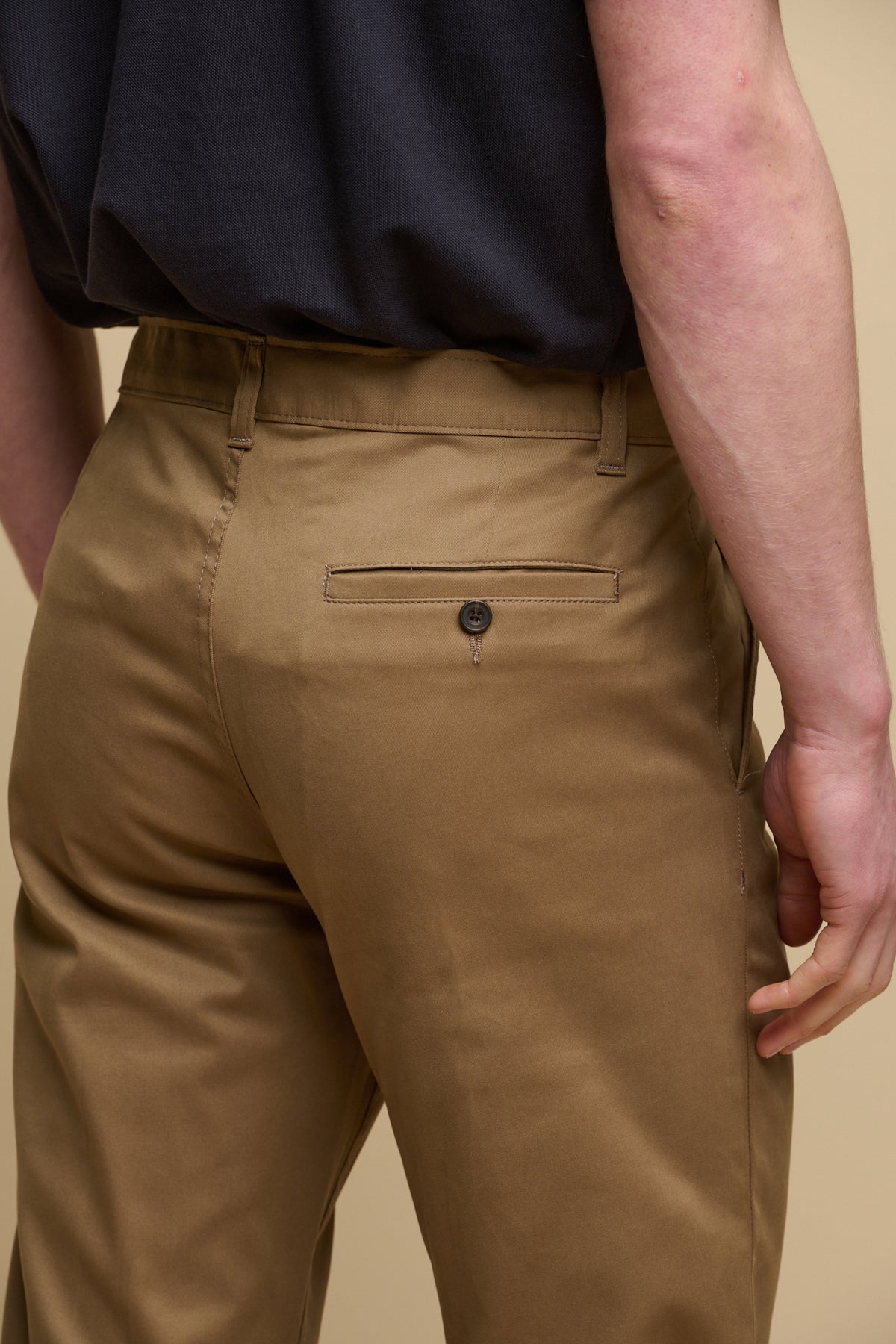 The back pocket detail shot of male wearing men's slim stretch chino in khaki, back pocket on right with button fastening