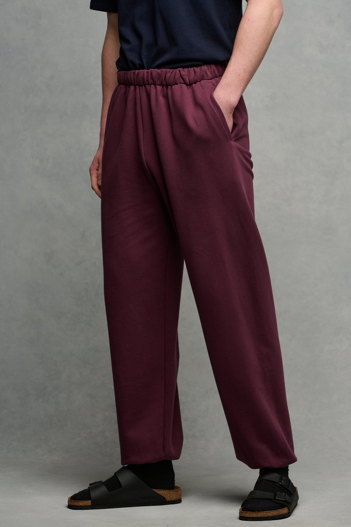 Waist down image of male with hands in pockets wearing sweatpants in plum