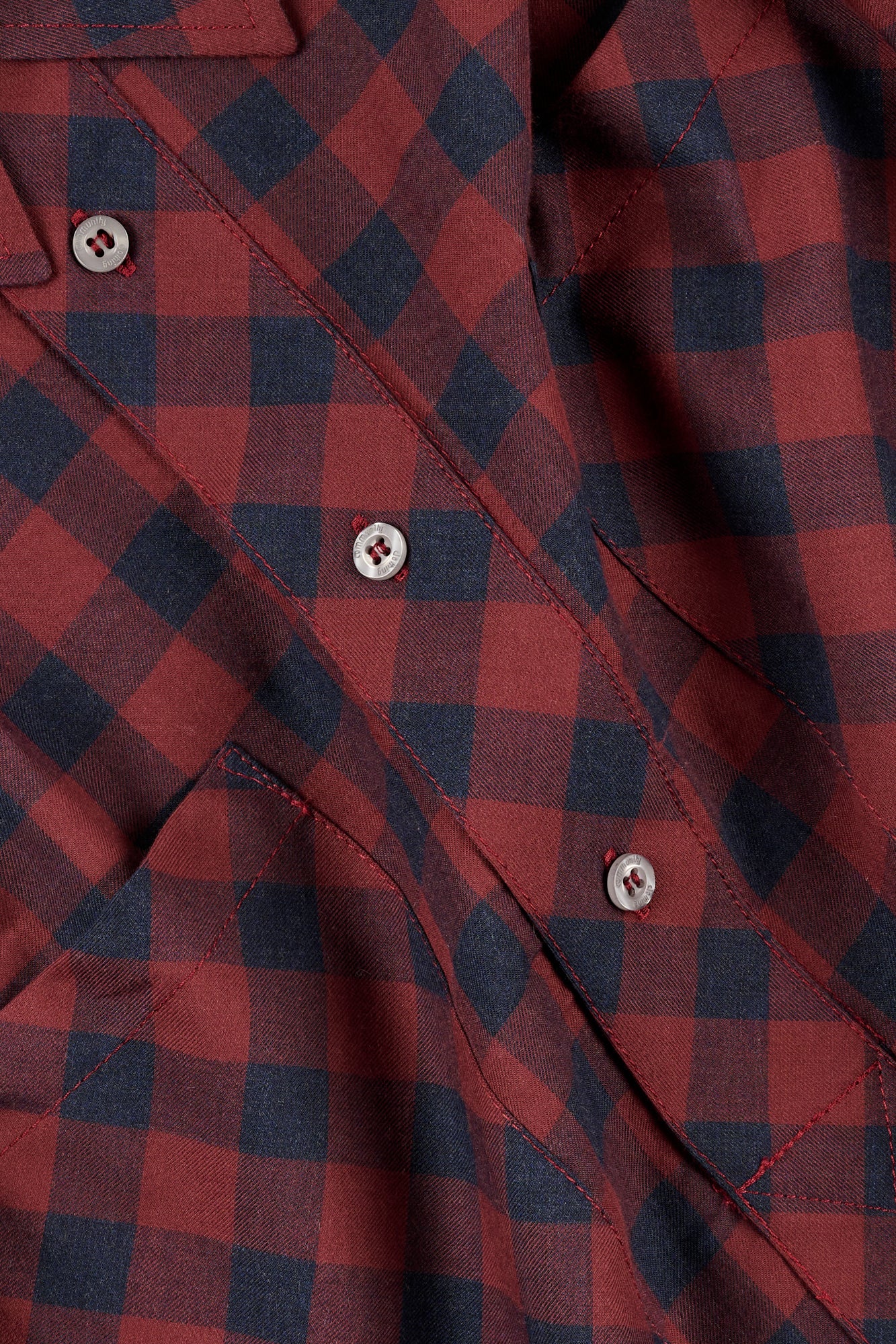 Close-up of a red and navy checkered shirt with buttons.
