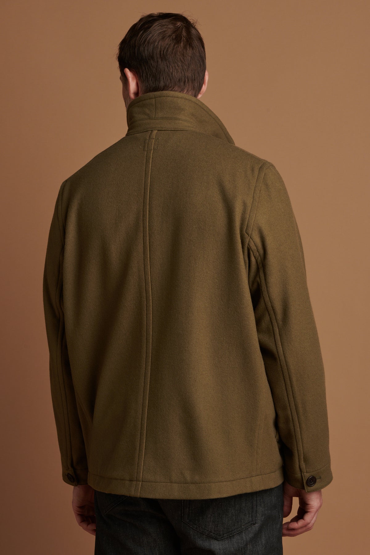 
            The back of Patrick Grant wearing Arthur wool chore jacket in olive with the collar up. 