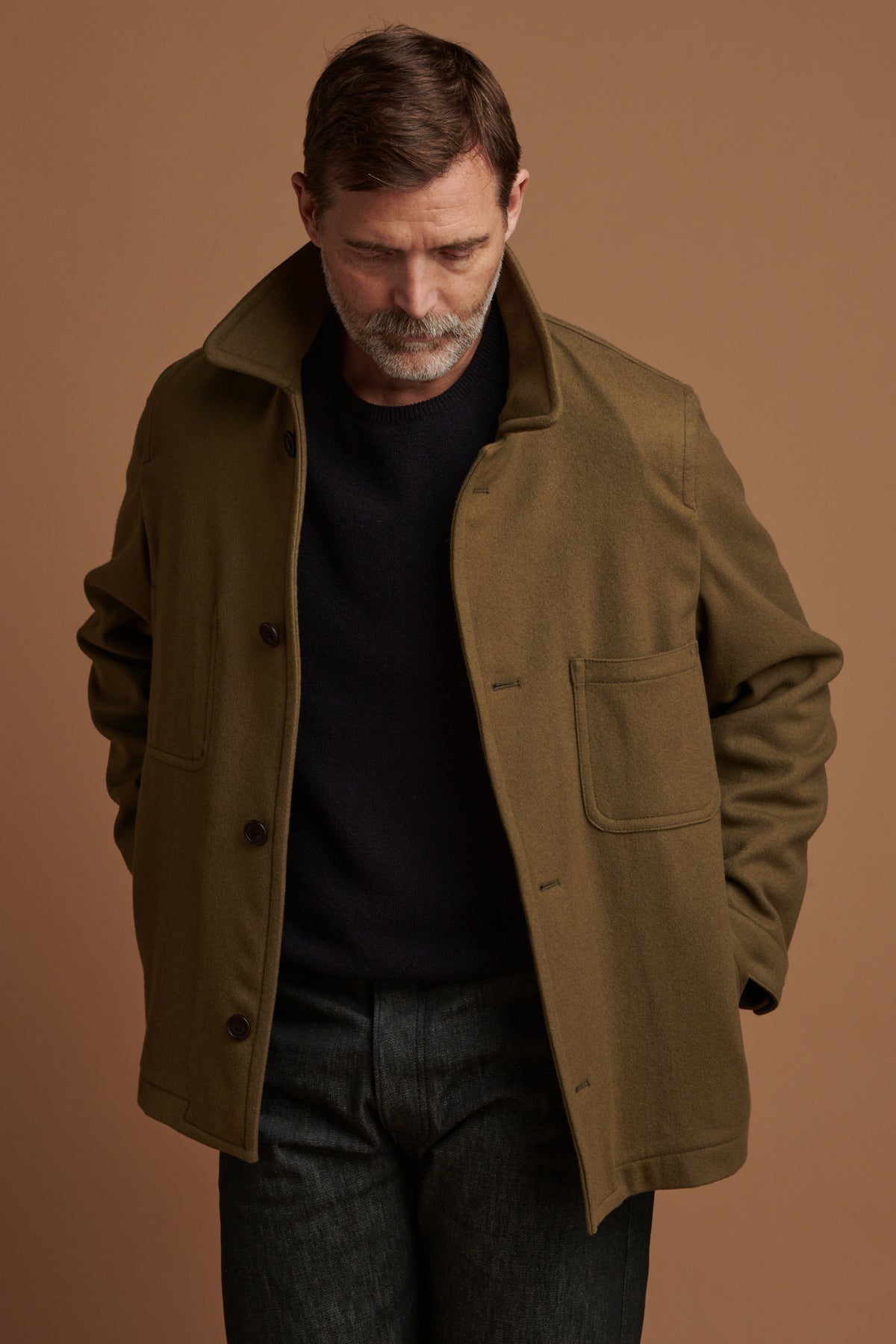 Patrick Grant wearing Community Clothing Arthur wool chore jacket in olive with the collar up. Worn over lambswool saddle shoulder crew neck in navy.