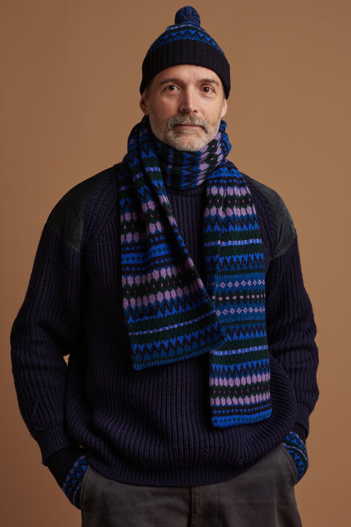 
            Patrick Grant wearing fair isle lambswool hat scarf and glove bundle set in navy, over fisherman ribbed jumper in navy