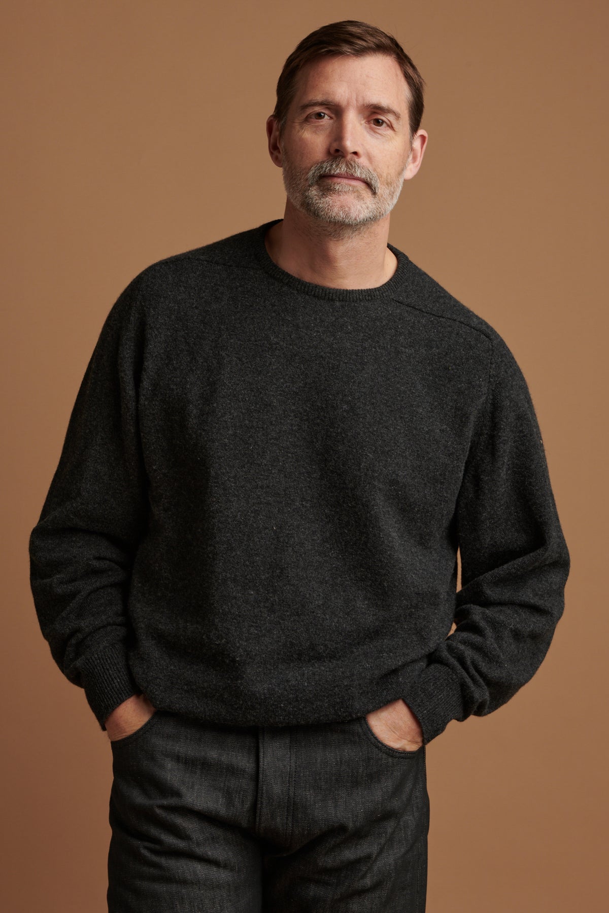 
            Patrick wearing lambswool saddle shoulder crew neck jumper in charcoal  paired with loose fit button fly Arran jean in black