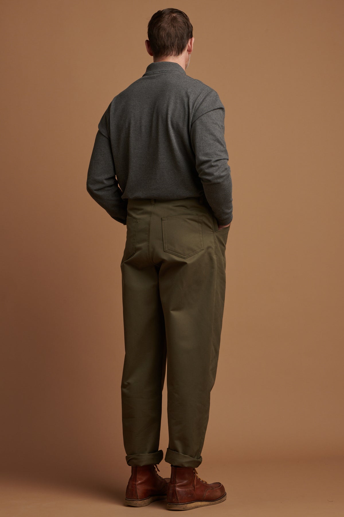 
            The back of Patrick wearing cotton chore trousers in olive with the hem rolled up