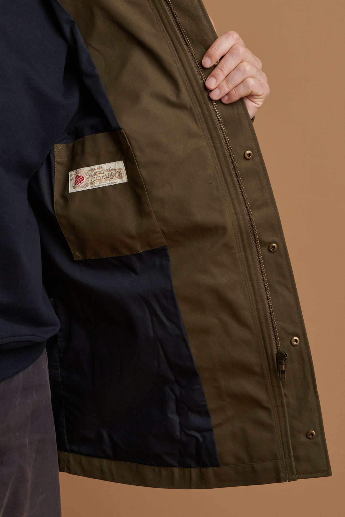 The inner lining of waxed mountain parka in olive with inside pocket showing British Millerain label