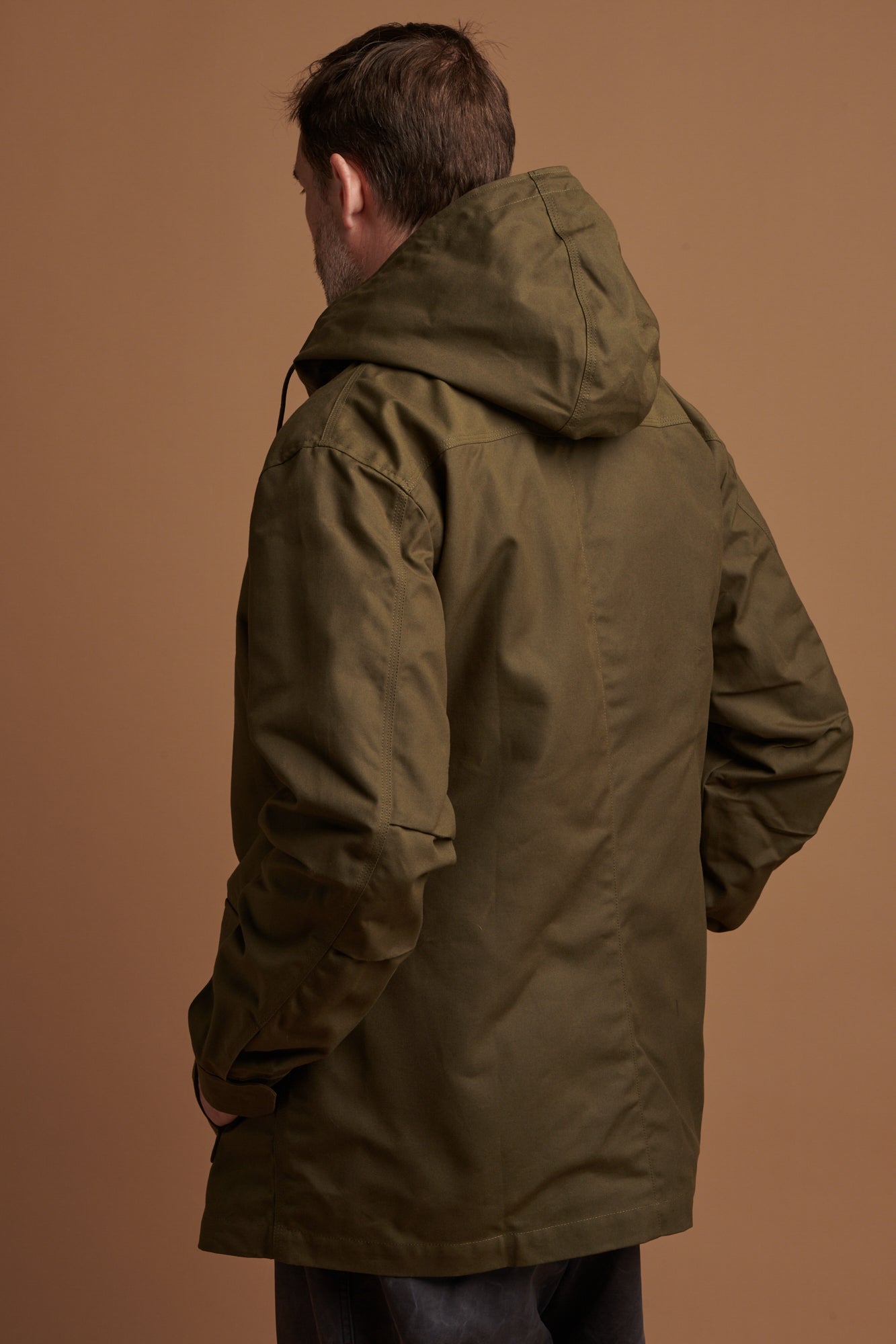 Patrick Grant wearing Community Clothing waxed mountain parka in olive with zip fastening as well as press studs. Three external pockets