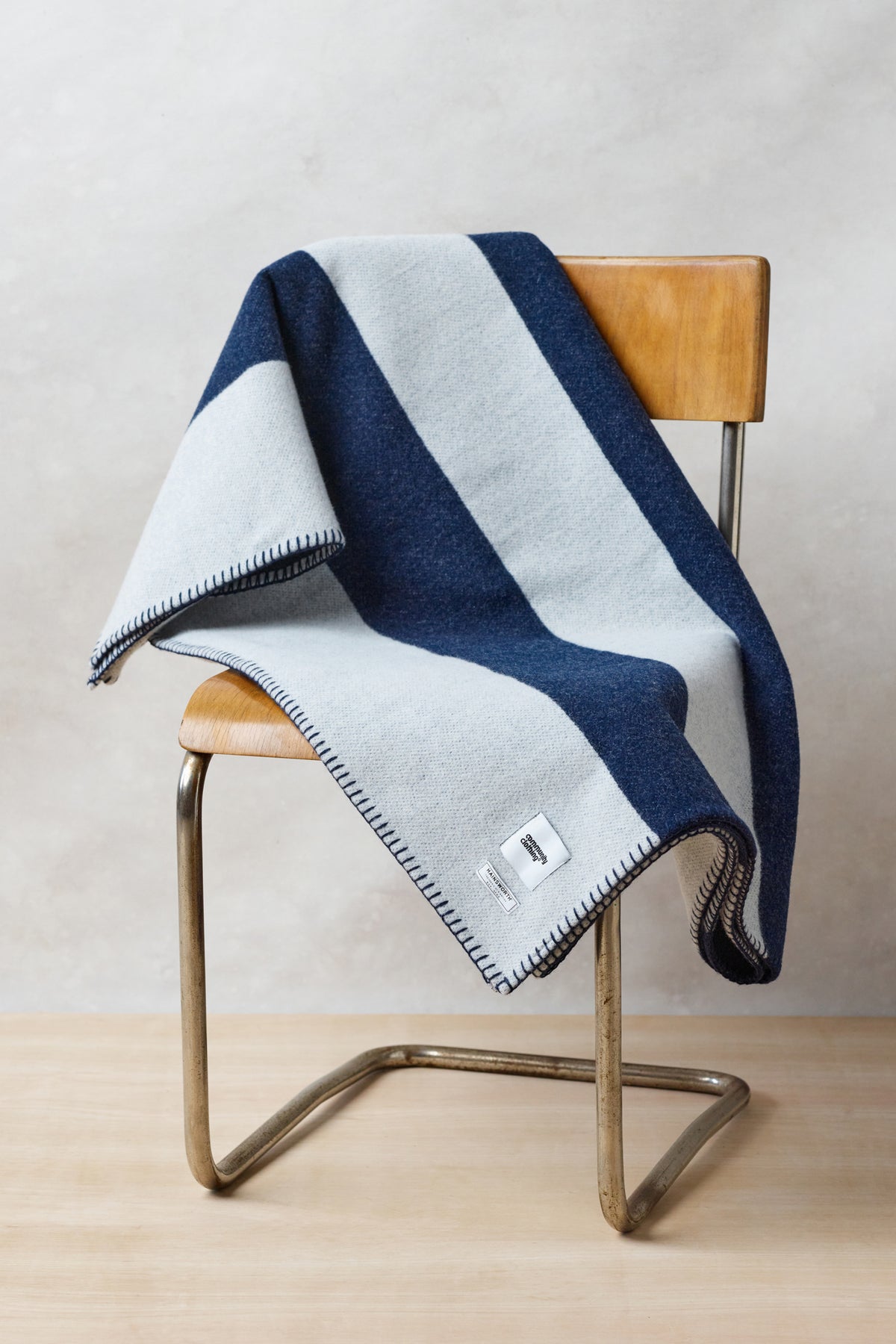 
            Image of pure wool striped blanket in navy ecru draped over vintage chair