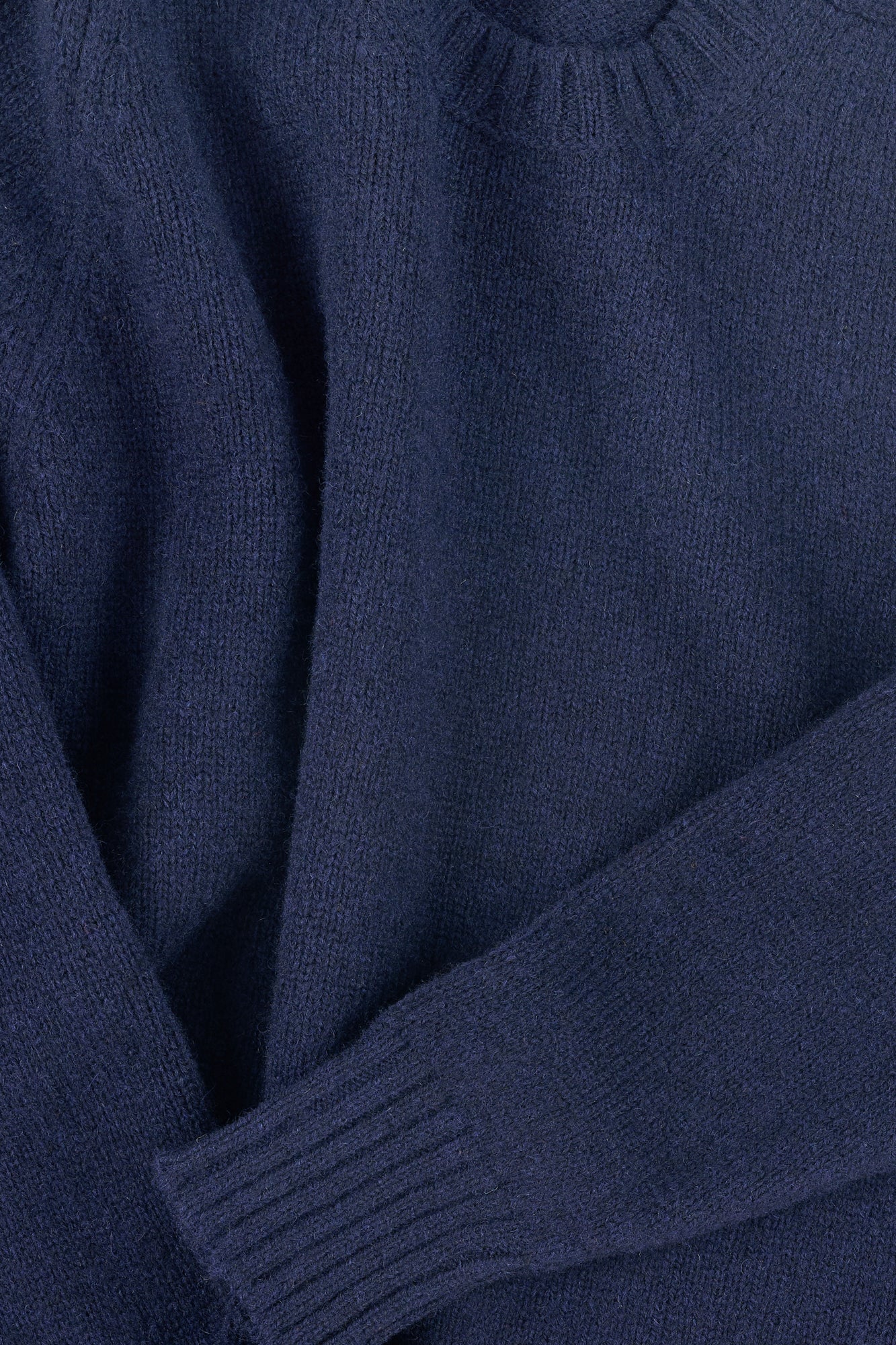 Close-up of a navy blue sweater with ribbed cuff and hem