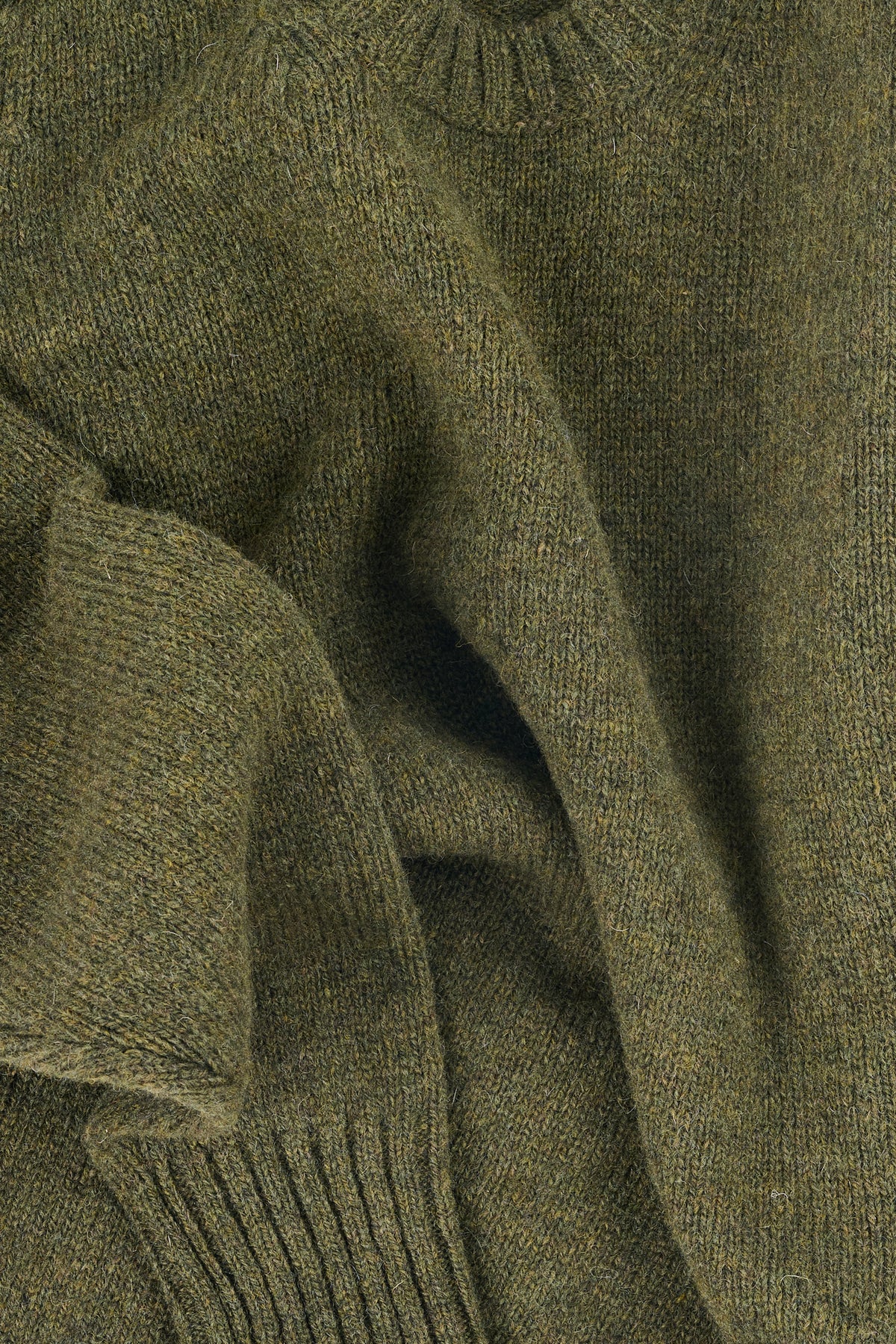 Close up of a green marled knitted jumper with rib neckline and cuffs.
