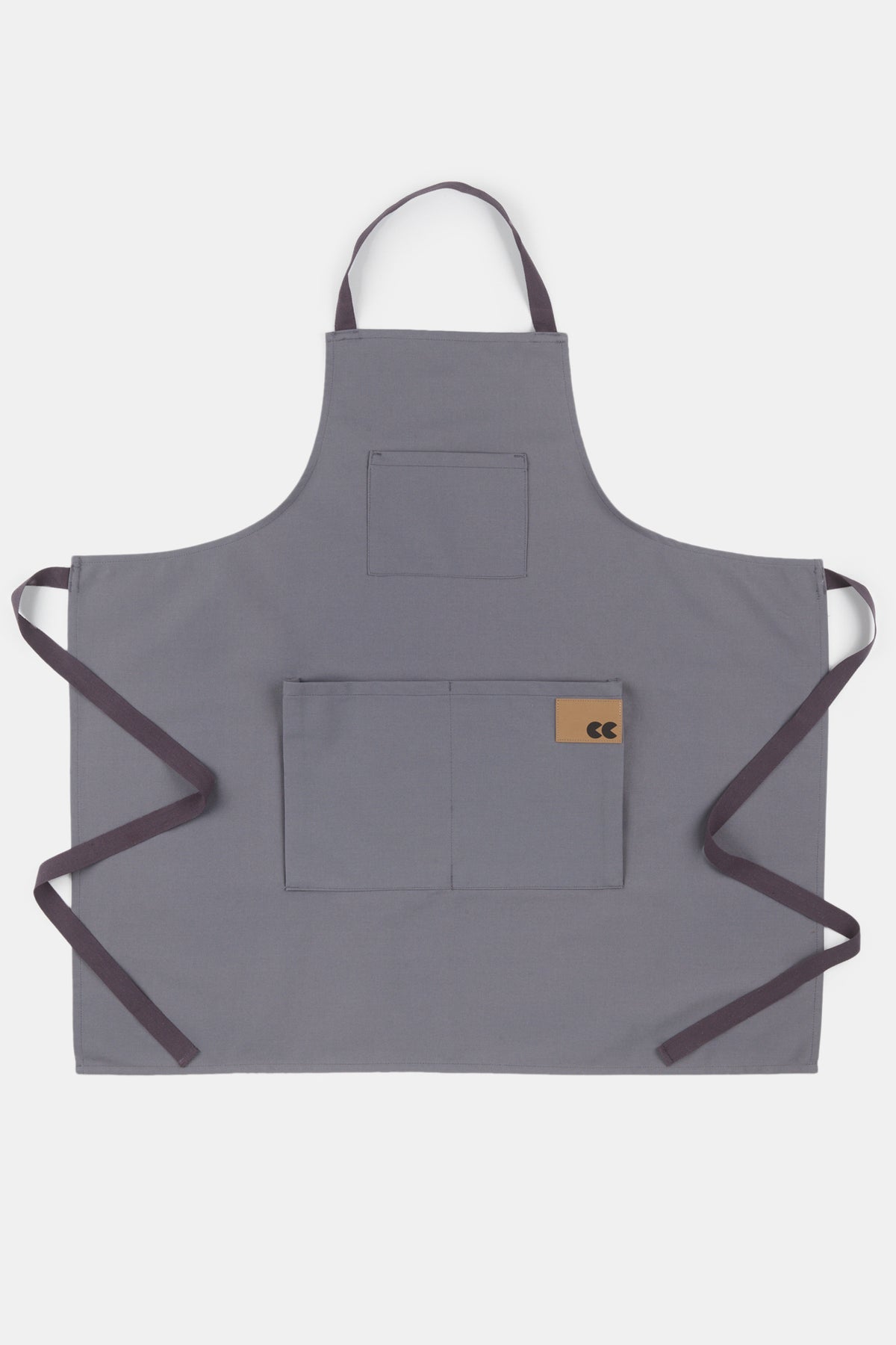 
            Flatlay product shot of apron in slate, three front pockets with CC logo brown patch and slightly darker slate ties