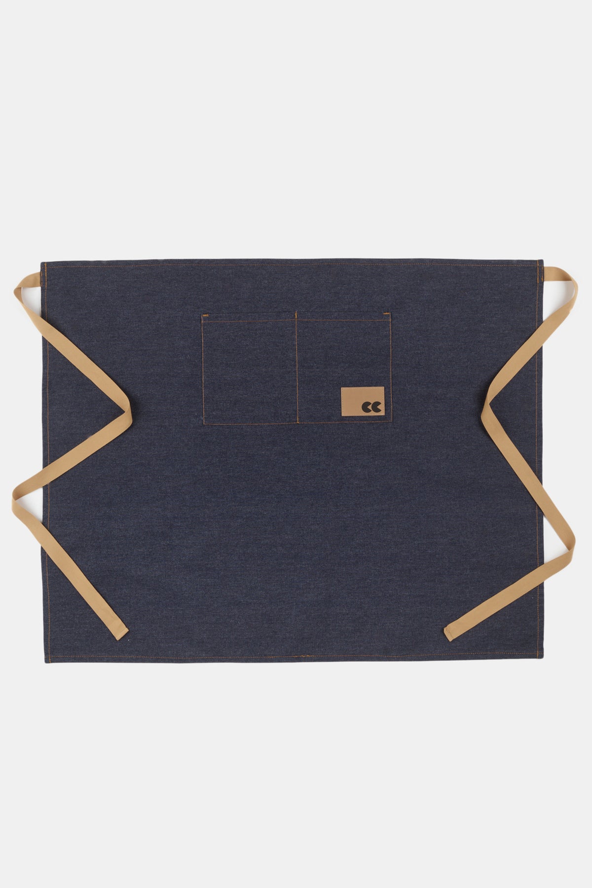 Flatlay of unisex half apron in indigo denim, two front pockets