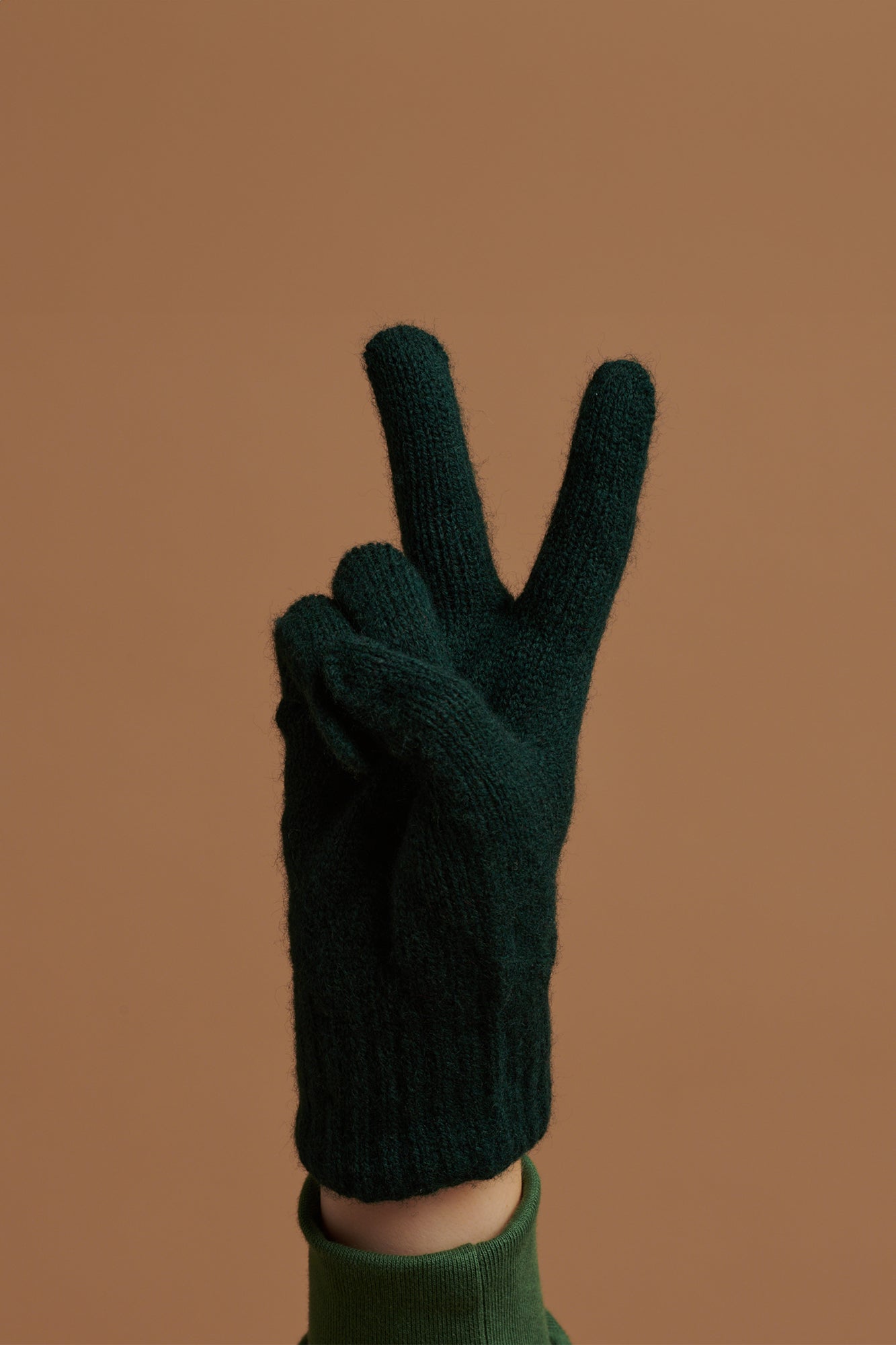 Hand wearing bottle green lambswool glove doing a peace sign