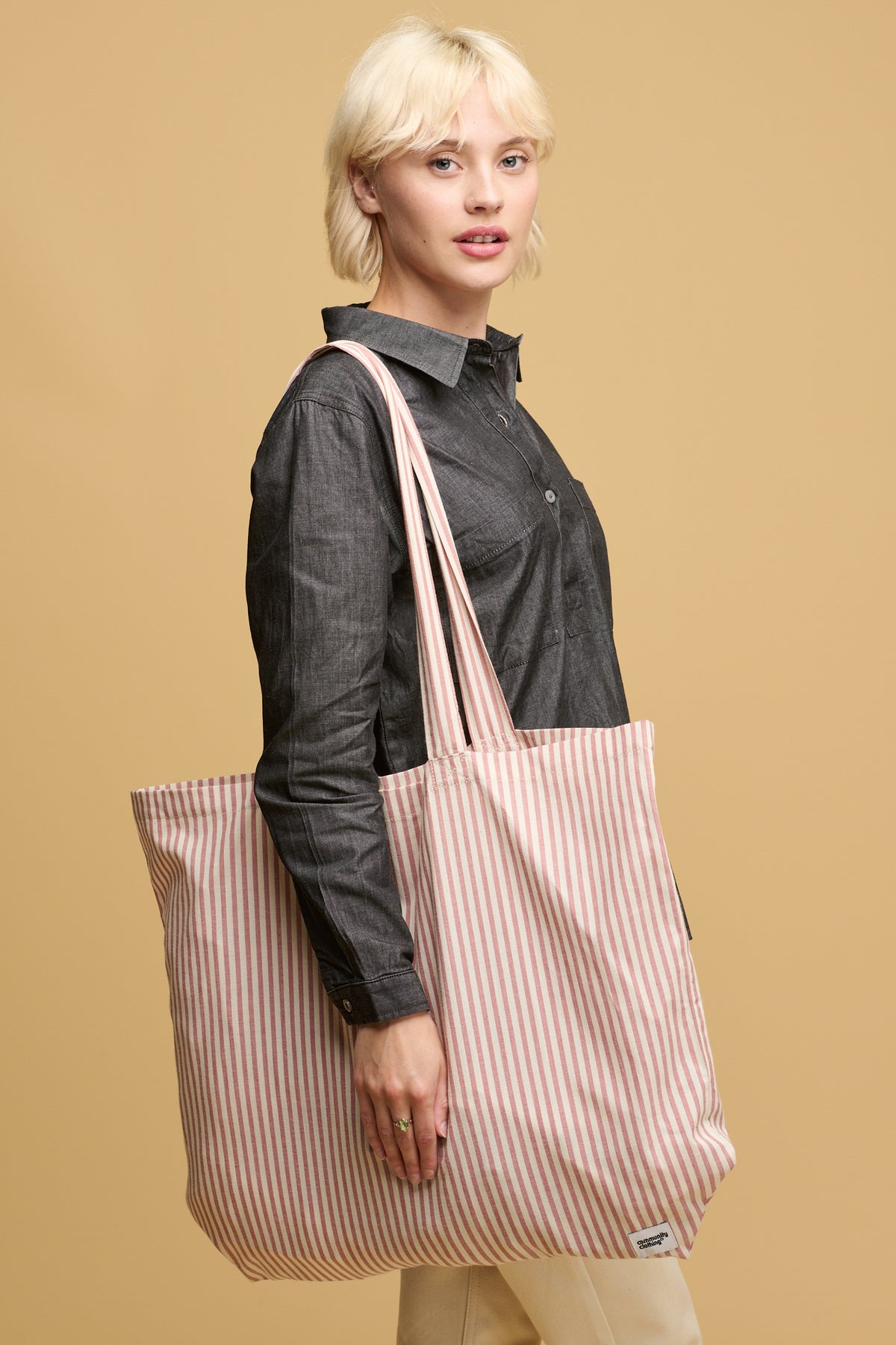 Female wearing quarry bank mill stripe tote bag in red and white stripe with small Community Clothing logo in the bottom right corner of the bag