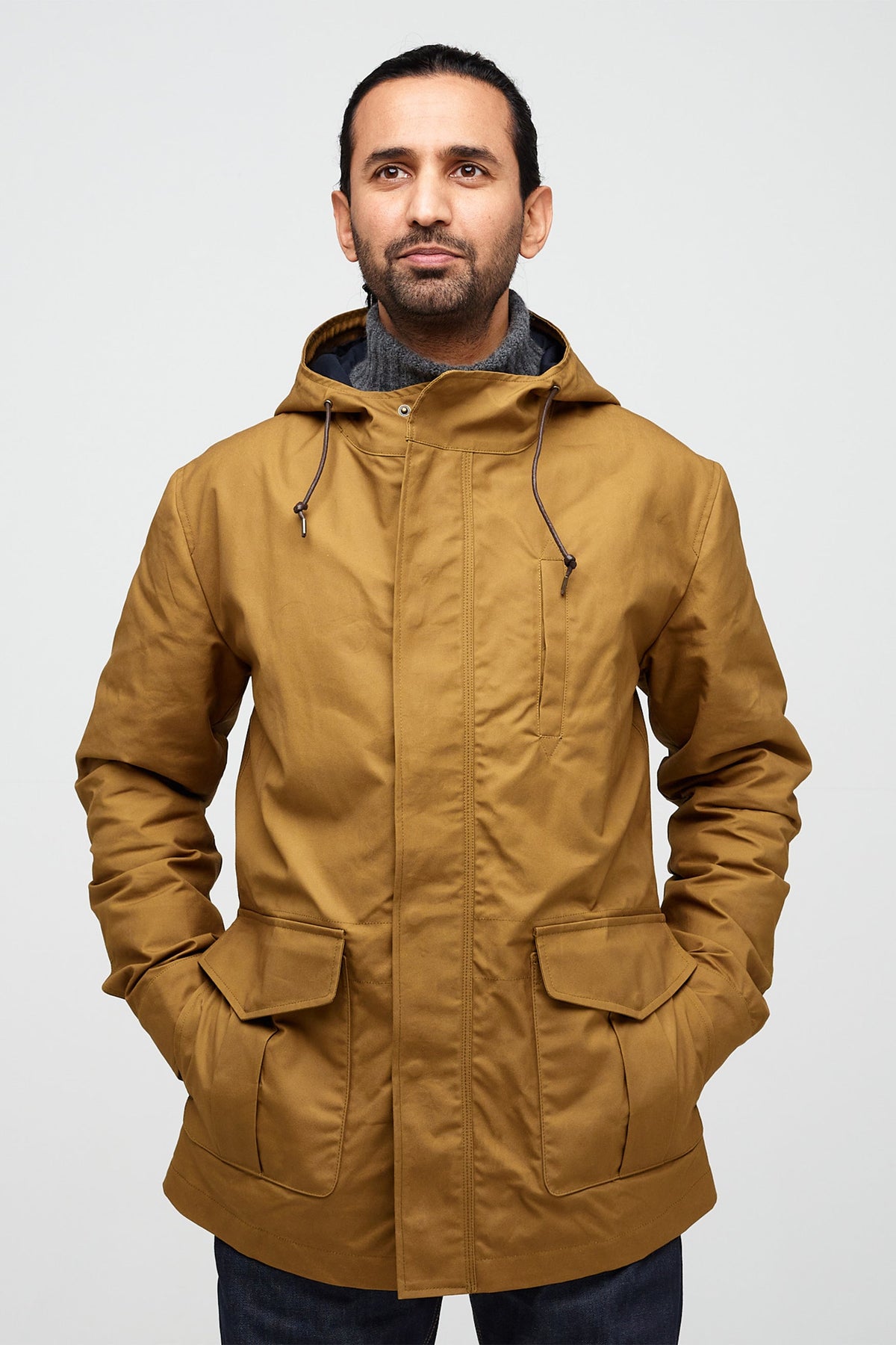 
            male wearing mountain parka in tan with hands in front pockets 